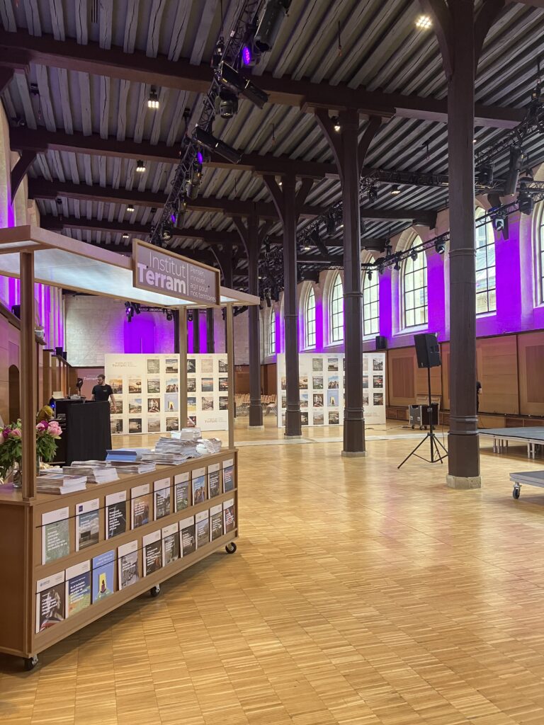 Exposition professionnelle, avec stand d’accueil, panneaux d’exposition et mise en lumière événementielle violette.